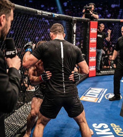 Two fighters in a cage fight scenario with a referee and camera in the background, featuring UFC branding.
